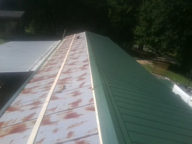 Old rusted panels beside newly installed green metal roofing — Wind Damage Roof Repair by Roofing Brothers in Proctor