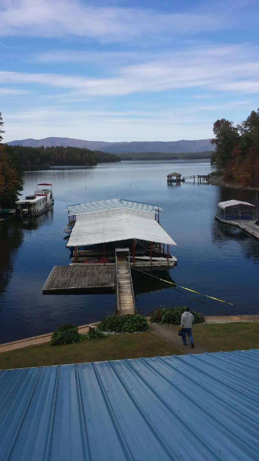 View across a lake from a newly installed blue metal roof in Proctor